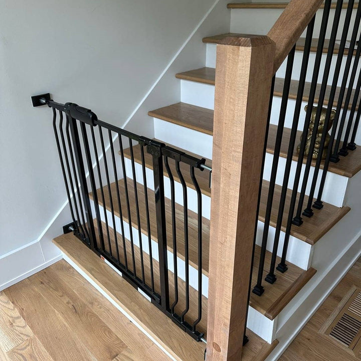 FairyBaby W046 black metal extra wide baby gate pressure mounted at the bottom of stairs with wooden bannister