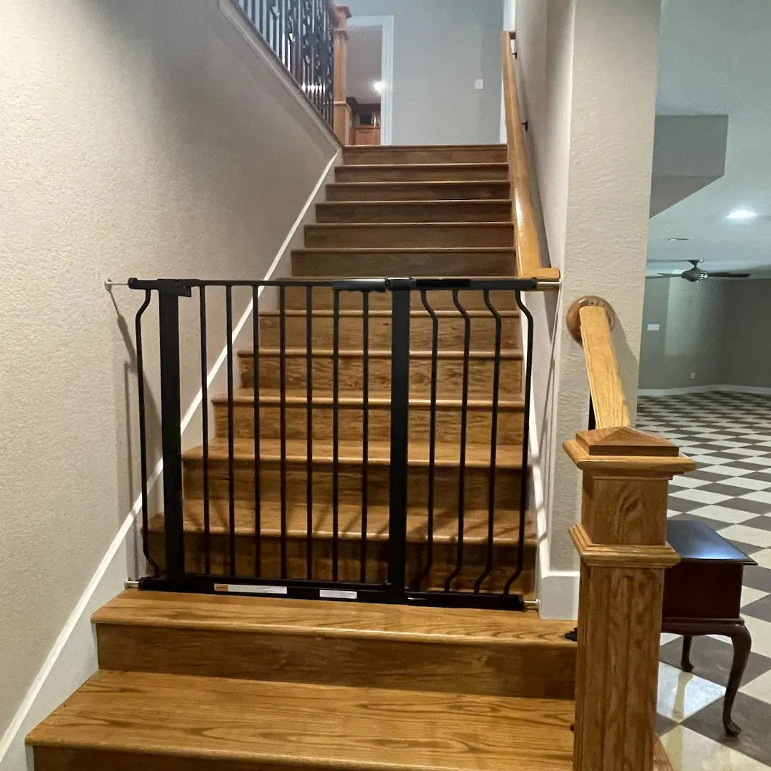 FairyBaby W282 black safety baby gate installed at the bottom of a modern hallway staircase