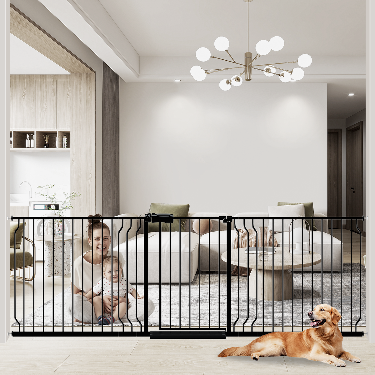 An extra wide baby gate installed in a home, with a black metal frame and a child sitting on a couch in the background. A dog is lying down in front of the gate.